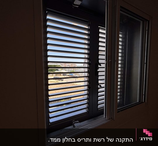 חלון עם תריסים פתוחים ונוף חיצוני